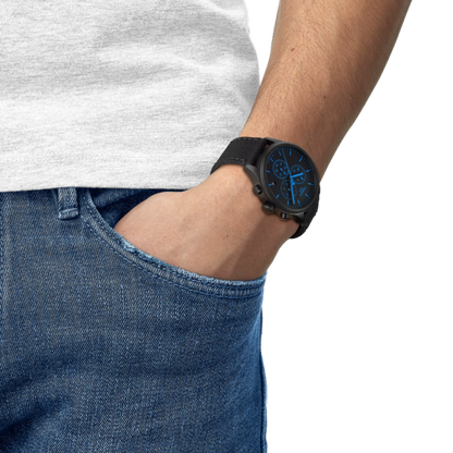 Person wearing a black watch with a blue face, gray shirt, and blue jeans on a white background