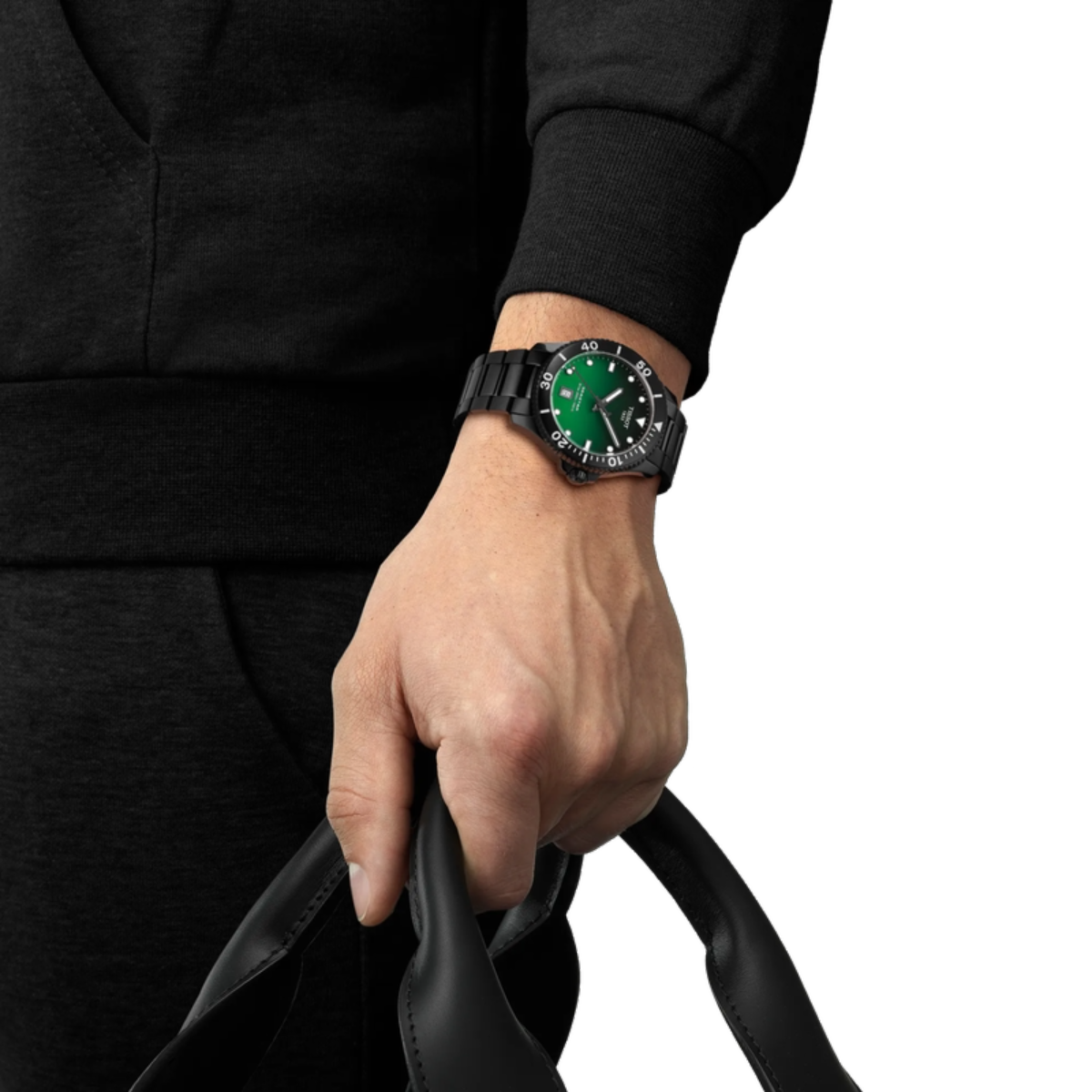 Hand wearing a black watch with a green face, holding a black leather strap.