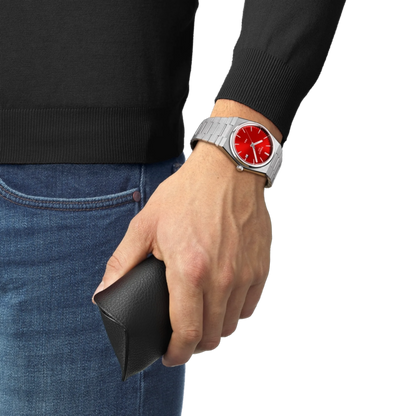 Hand wearing a watch with a red face, holding a black wallet, on a white background