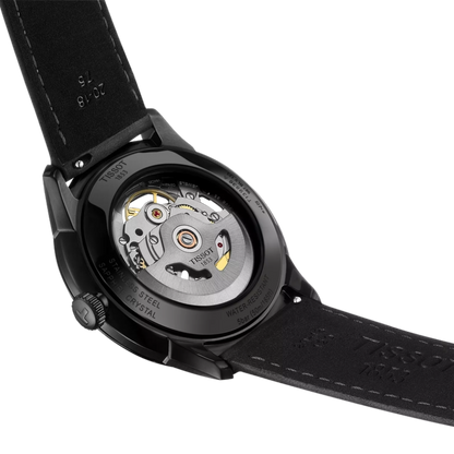 Close-up of a Tissot watch with visible movement and black strap on a white background