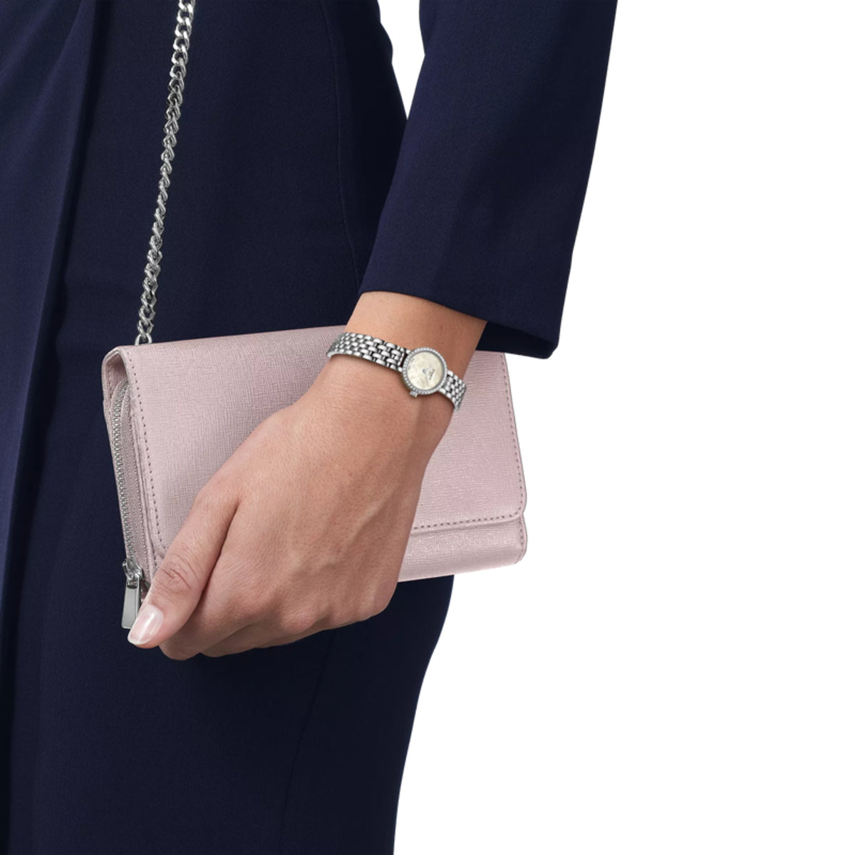 Hand holding a pink clutch with a silver chain, wearing a watch on a white background