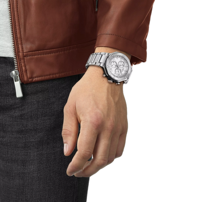 Hand wearing a silver watch with a brown leather jacket on a white background