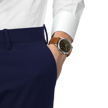 Person wearing a white shirt, navy pants, and a brown leather watch on a white background
