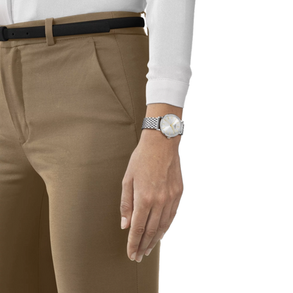 Person wearing beige pants and a white shirt with a watch on a white background