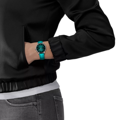 Person wearing a black jacket and gray jeans with a turquoise watch on a white background