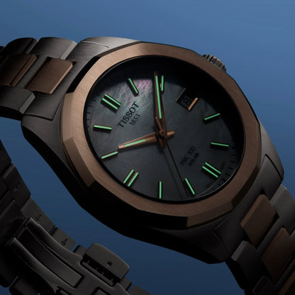 Tissot watch with brown strap and green accents on a blue background