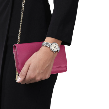 Hand holding a pink clutch with a watch on a white background