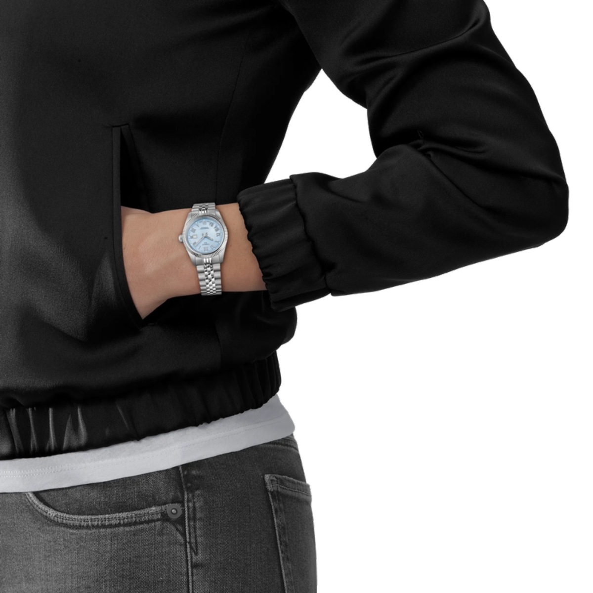 Person wearing a black jacket and gray jeans with a silver watch on a white background