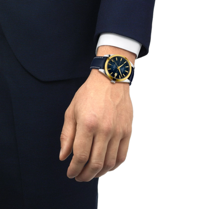 Hand wearing a watch with a blue strap and gold accents on a white background
