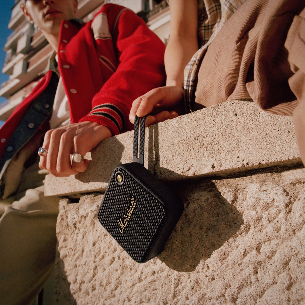 Person holding a Marshall speaker against a textured wall