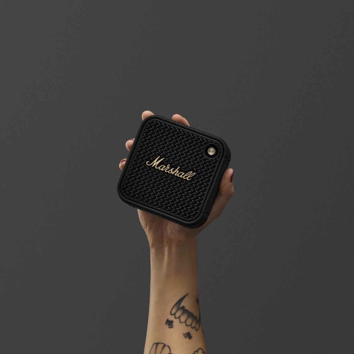 Hand holding a Marshall speaker against a dark background