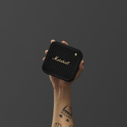 Hand holding a Marshall speaker against a dark background