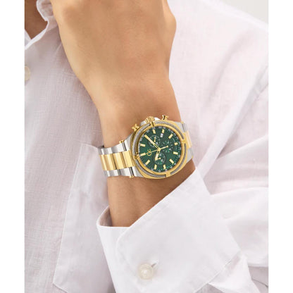 Gold and silver watch with green face on a wrist, wearing a white shirt.