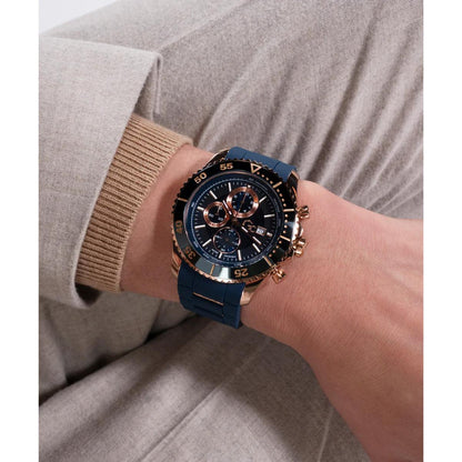Person wearing a blue watch with rose gold accents on a neutral background