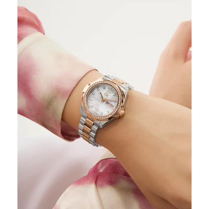 Rose gold and silver watch on a wrist with a blurred background