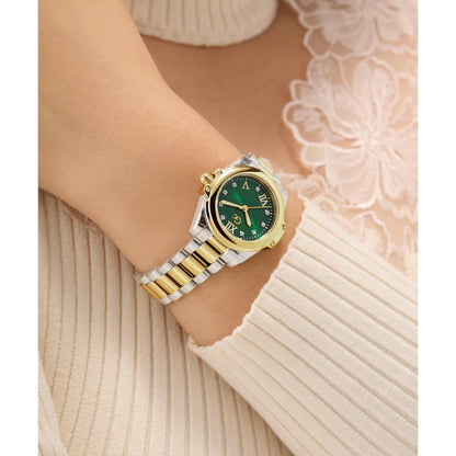 Gold and silver watch with green face on a wrist against a neutral background