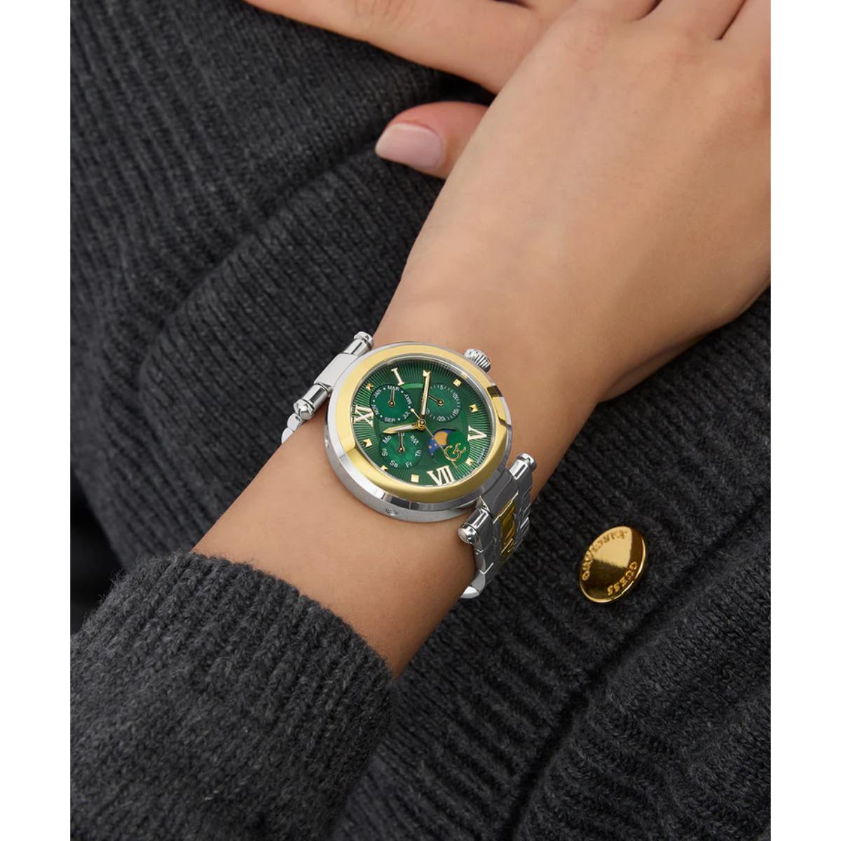 Wrist wearing a green and gold watch on a dark textured sweater background