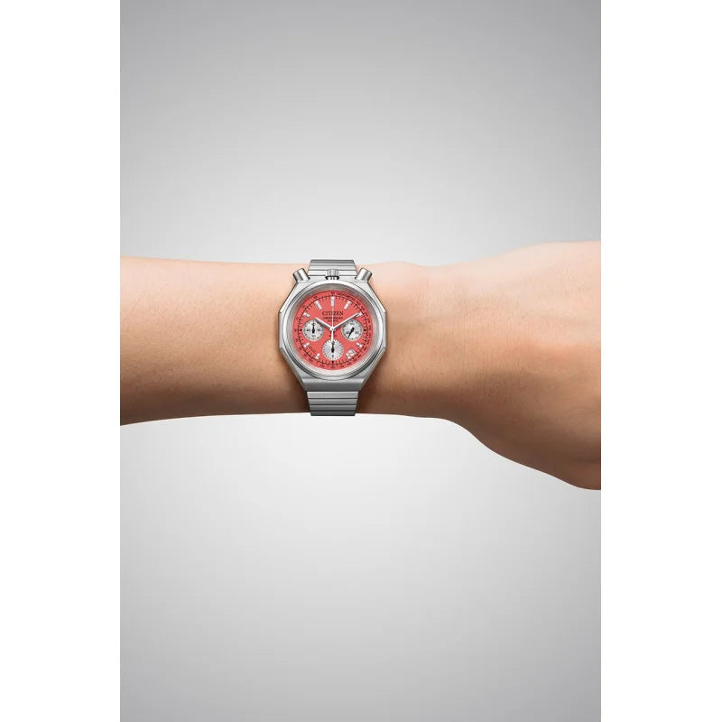 Silver watch with a red face on a wrist against a gray background