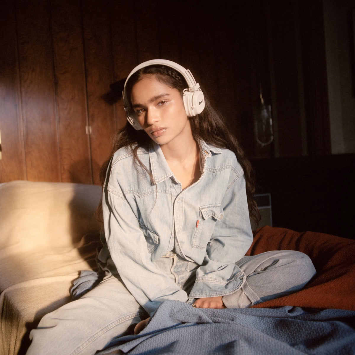Person wearing headphones sitting on a couch in a dimly lit room