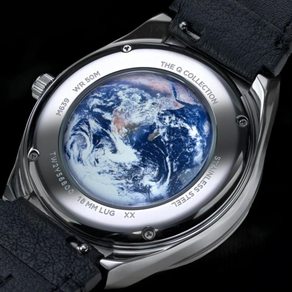 Watch with Earth image on the back, branded 'The Q Collection'.